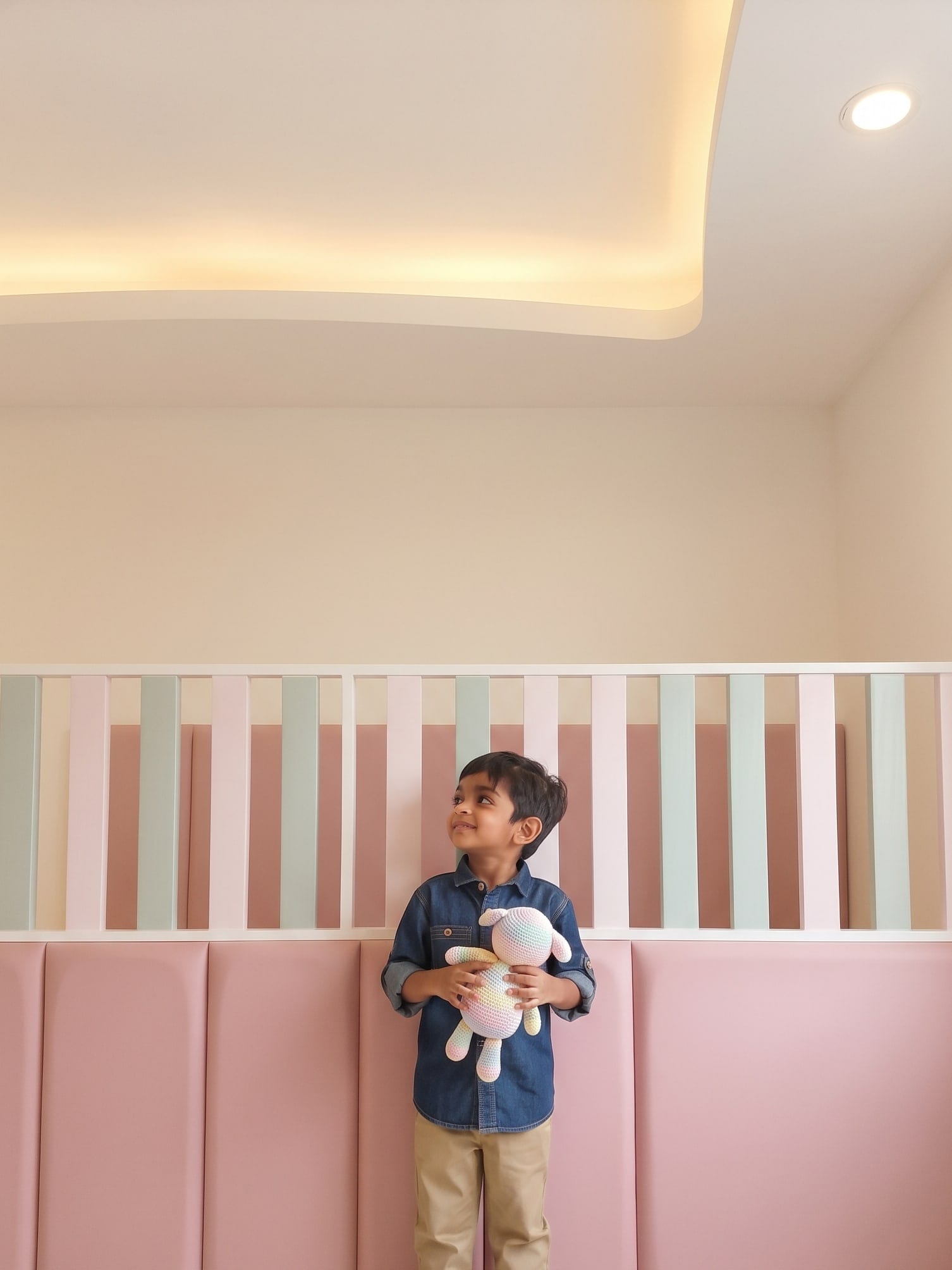 Children’s room with a padded pink wall and a pastel slatted headboard