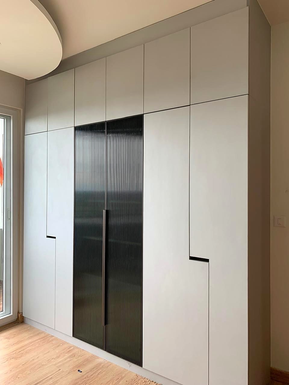 A finished wardrobe wall with a fluted glass tall unit
